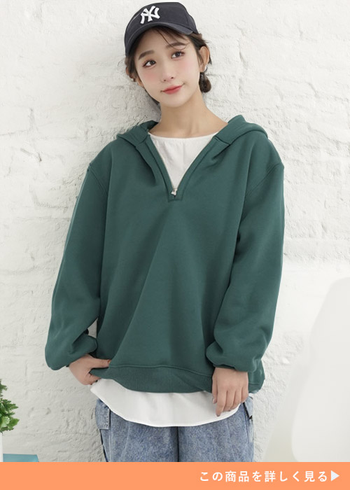 グリーンのハーフジップパーカを着る女性