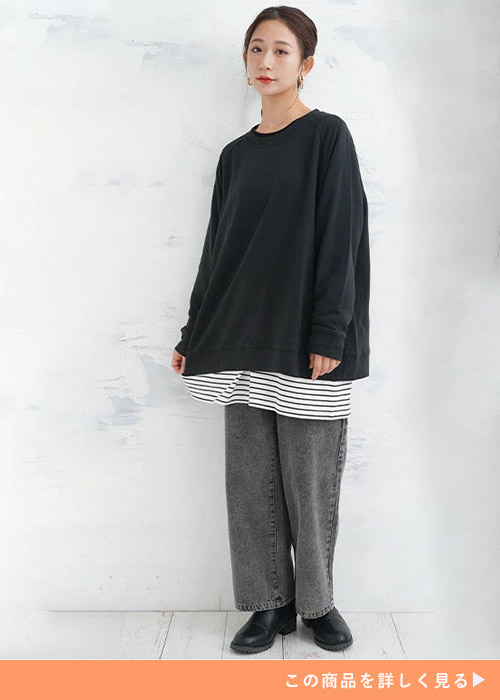 ボーダーT×黒トレーナーを着て、黒のデニムパンツをはく女性