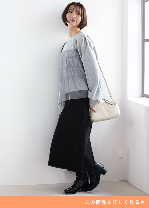 チュールをあしらったグレーのトレーナー×黒のタイトスカートを着る女性