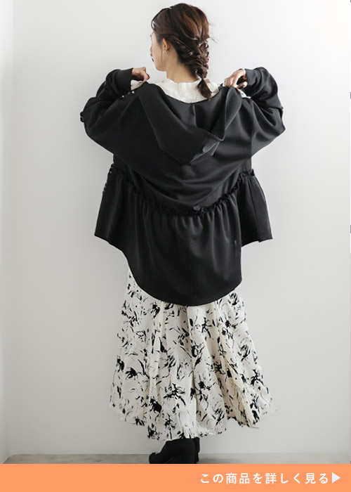 白トップス×白地に黒花柄のスカートを着て、黒のフリル付きパーカを羽織る女性