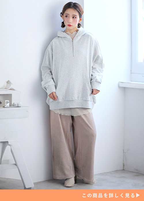 シアートップス×グレーのハーフジップパーカを着て、ブラウン系のワイドパンツを履く女性