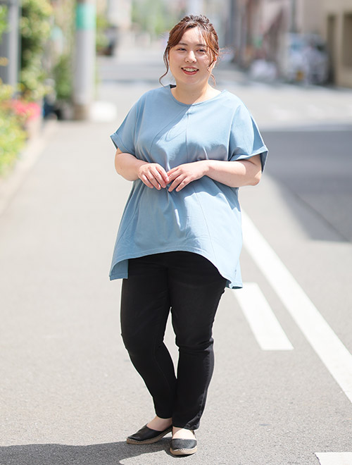 水色のトップスを着て、黒色のスキニーデニムパンツを履く女性