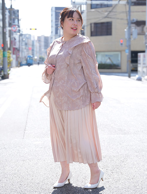 くすみピンクの花柄スカートを着て、ピンクベージュのプリーツスカートを履く女性