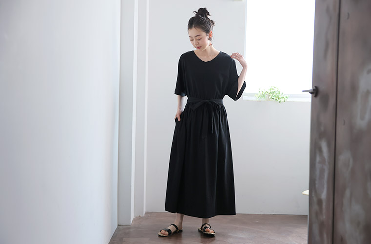 黒色のAラインワンピースを着て、リボンベルトでウエストマークする女性