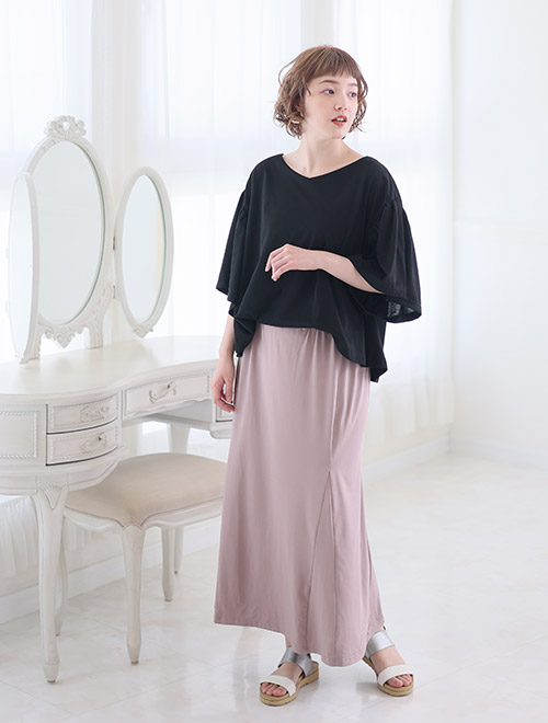 黒色のトップスとグレージュのマーメイドスカートがひとつになったドッキングワンピースを着る女性