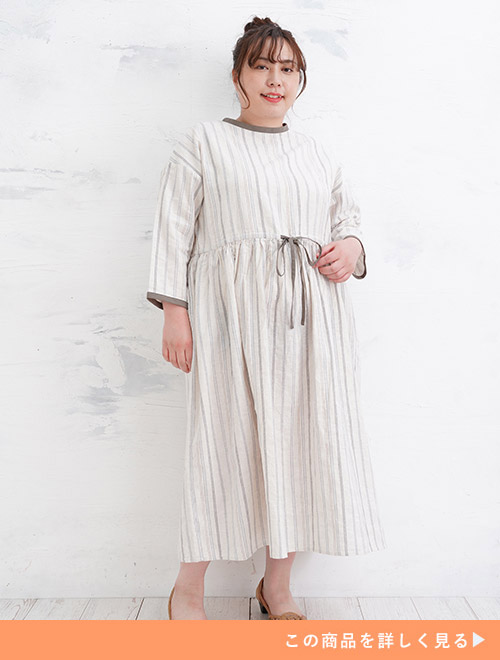 ベージュ色のストライプ柄ワンピースを着る女性