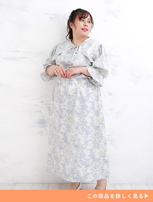 ボレロのようなえり元が特徴的な白地×水色の花柄ワンピースを着る女性