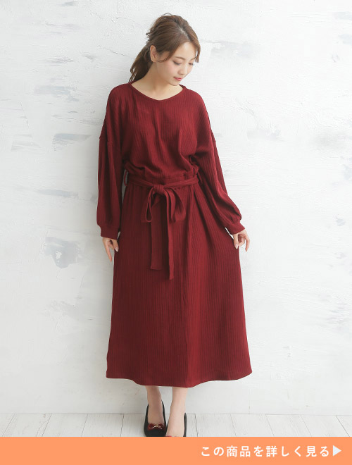 ウエストマークされたボルドーのニットワンピースを着る女性