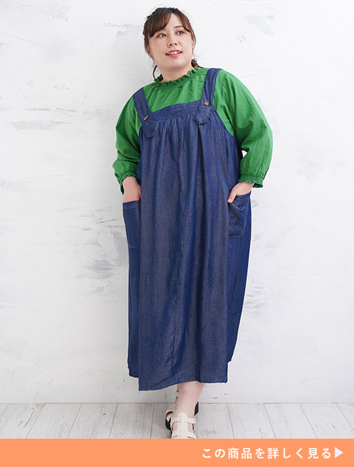 グリーンのブラウスにインディゴのデニム風ジャンスカを重ね着する女性