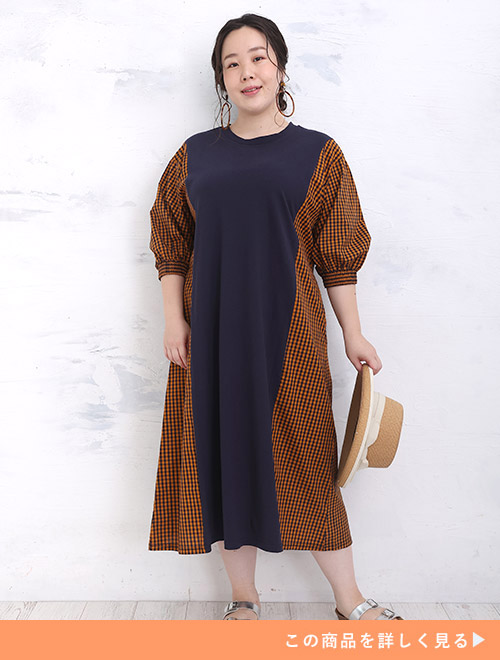 センターにネイビー、両サイドにネイビー×オレンジのチェック柄切り替えワンピースを着る女性