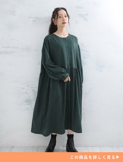 白の細ストライプを配したグリーンのワンピースを着る女性