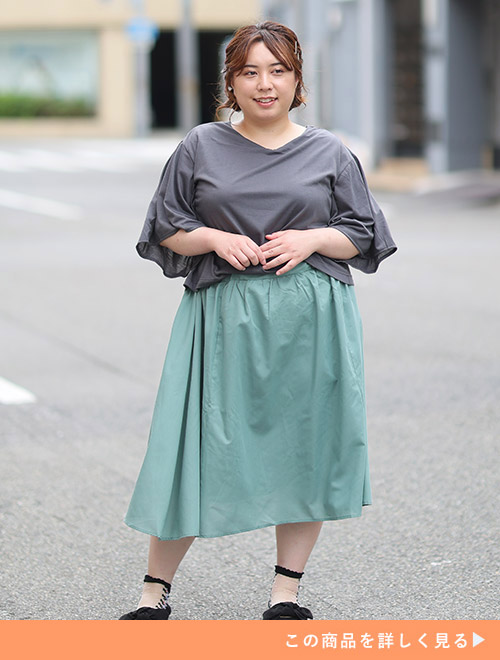 グレーのトップス×くすみグリーンのスカートをドッキングしたワンピースを着る女性