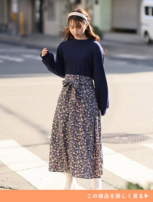 ネイビーのトップスを花柄スカートにトップスインしたようなドッキングワンピースを着る女性