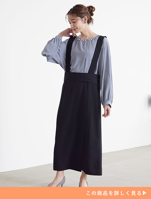 くすみブルーのパール付きブラウスに黒のジャンスカを重ねて着る女性