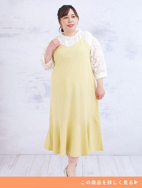 白のレーストップスを着て、イエローのキャミワンピを重ね着する女性