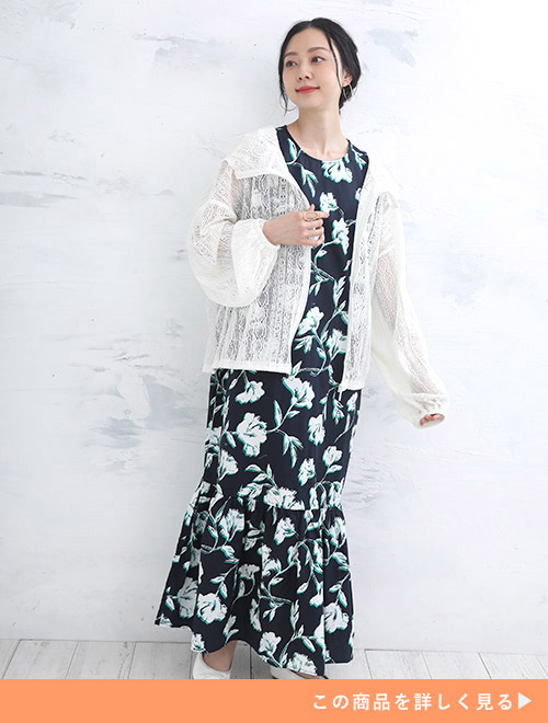 ネイビーの花柄ワンピースに、アイボリーのレース網パーカを羽織る女性。