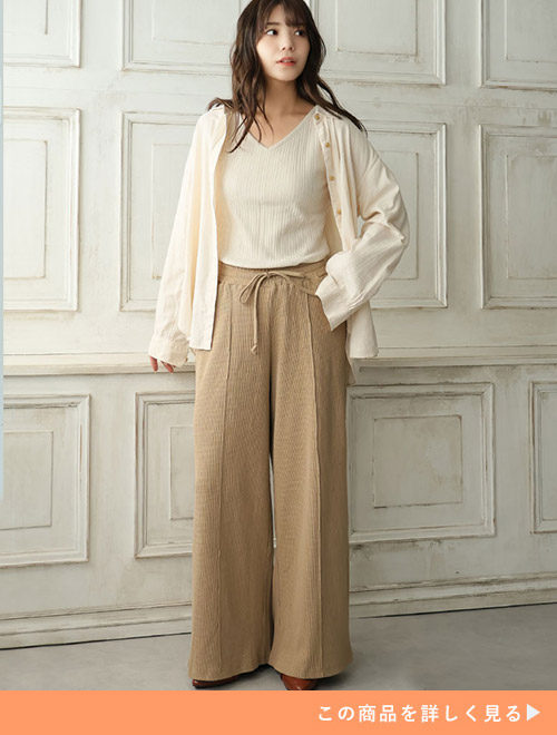 アイボリーのトップス×グレージュのワイドパンツに、オフホワイトのシャツを羽織る女性