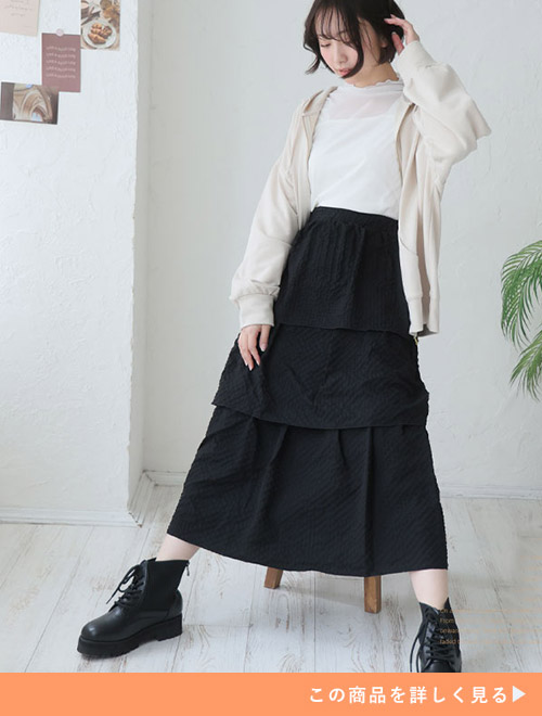 白のシアートップス×黒のティアードスカートに、ベージュのパーカを羽織る女性