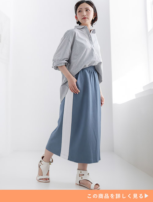 ストライプ柄のシャツ×サイドラインの入ったスモークブルーのスカートを着る女性