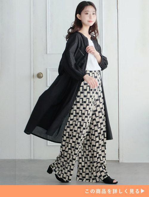 白トップス×柄パンツに、黒のシャツワンピースを羽織る女性