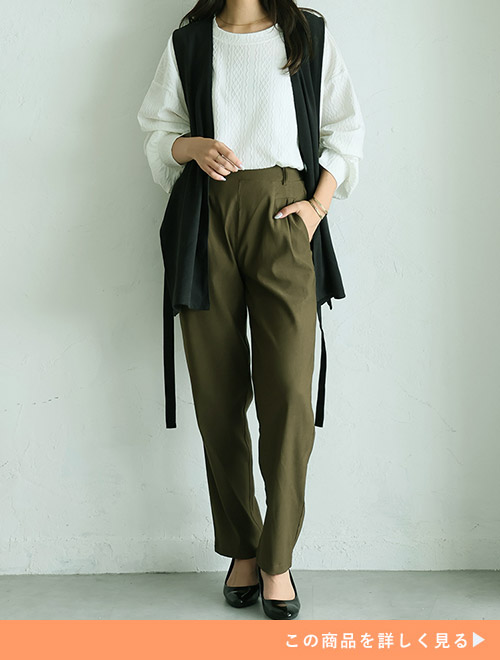 白トップス×カーキのテーパードパンツに、黒のジレを羽織る女性