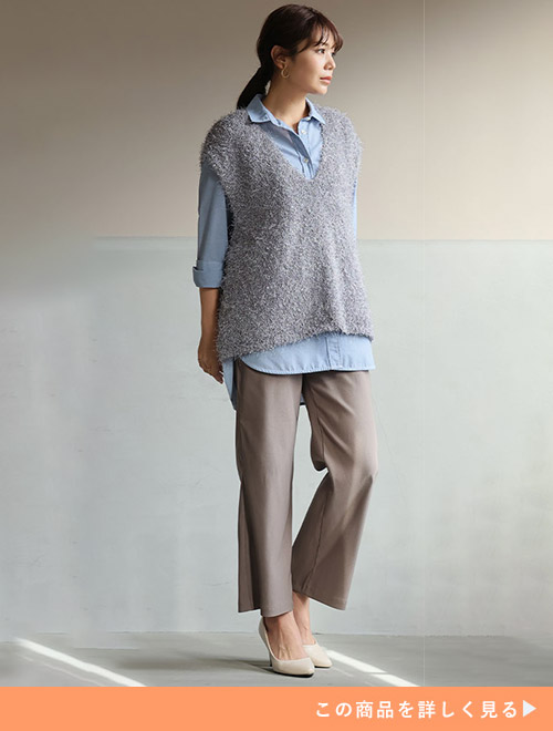 ブルーのシャツ×グレーニットに、モカ色のパンツを履く女性