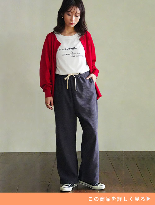 白のロゴT×チャコールのワイドパンツに、赤のカーディガンを羽織る女性