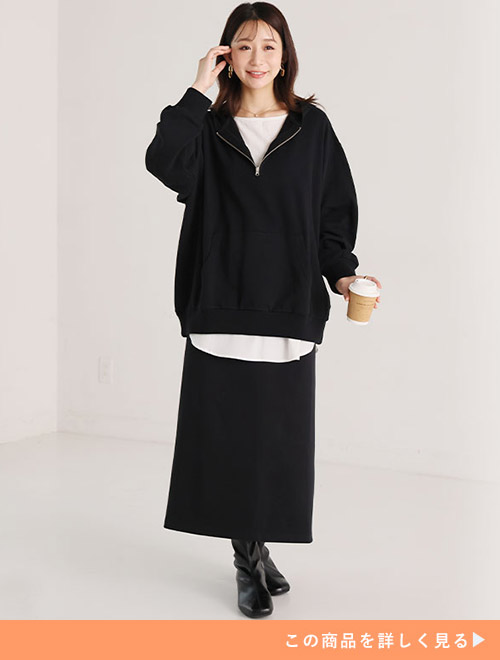 白トップスに黒のハーフジップトップスを重ね着し、黒のタイトスカートを履く女性