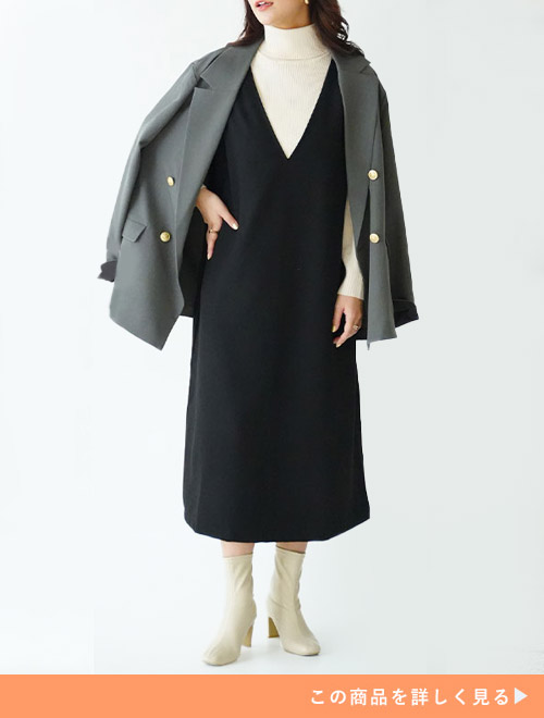 白のタートルネックニット×黒のジャンスカにグレーのジャケットを肩掛けする女性