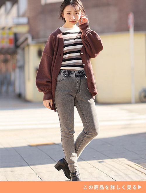 加工ありブラックのパンツとボーダートップのコーデに、ブラウンカーディガンを羽織る女性