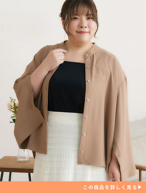 ブラックトップスとホワイトスカートのコーデに、モカのとろみ素材シャツを羽織る女性