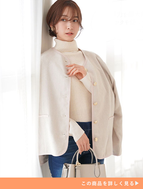 デニムパンツとホワイトタートルニットのコーデにアイボリーのジャケットを羽織る女性