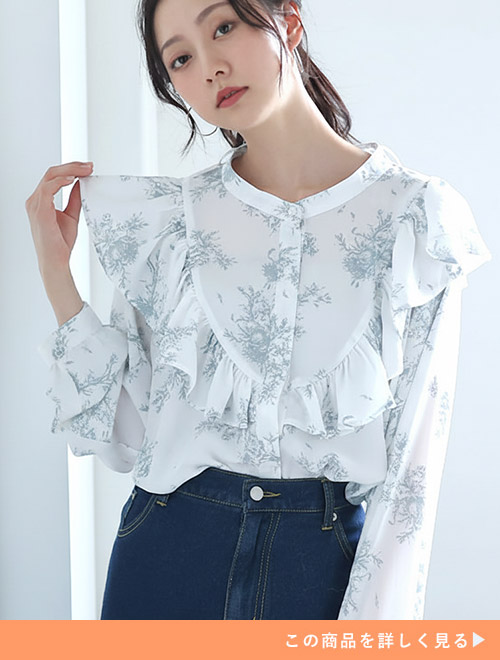 ライトグレーの花柄フリルブラウスにインディゴデニムボトムを合わせる女性