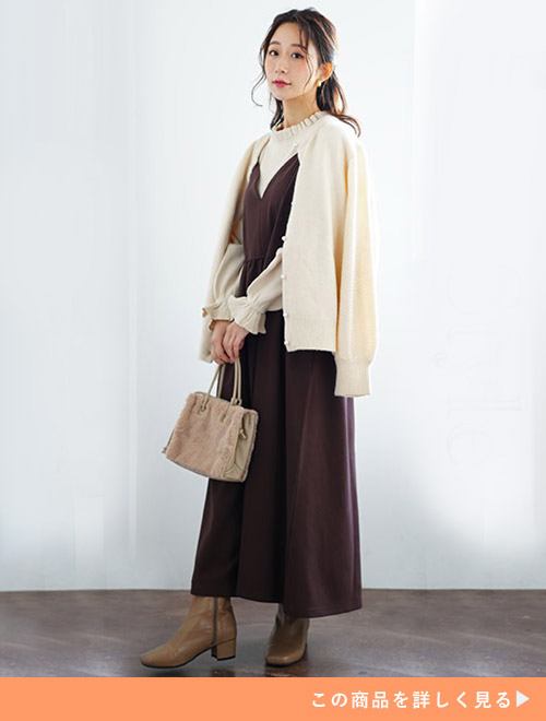 ホワイトインナーとブラウンワンピースのセットアップに、ホワイトのカーディガンを羽織る女性