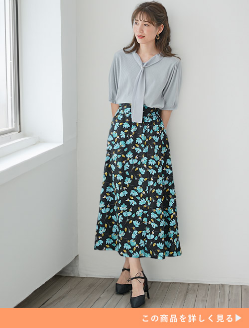 花柄スカートにブルーのボウタイデザインブラウスを合わせる女性