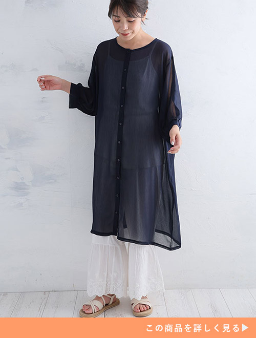 ホワイトレースパンツとホワイトトップスのコーデに、ネイビーシフォンワンピースを重ね着する女性