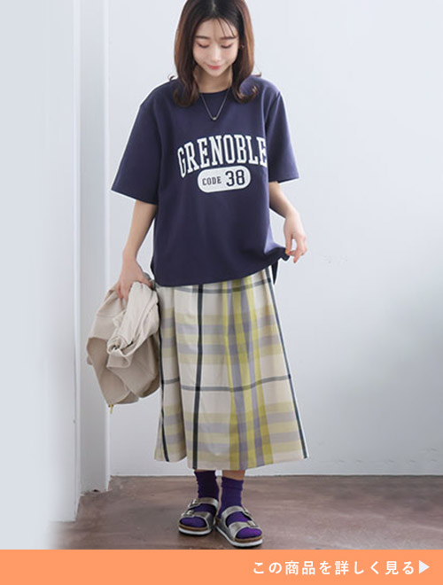 チェックスカートにネイビーのカレッジプリントTシャツを合わせる女性