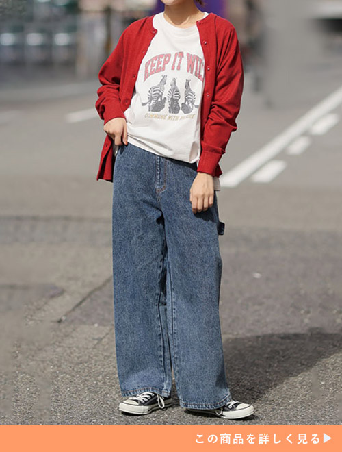 ネイビーケミカルパンツと白Tシャツのコーデに、レッドカーディガンを羽織る女性