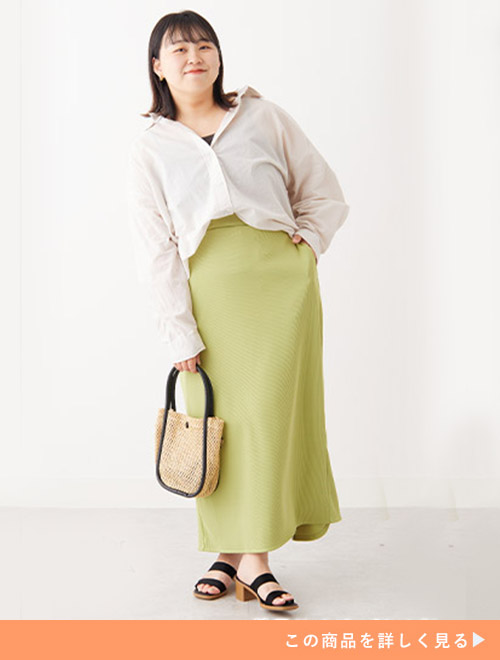 ライムタイトスカートとブラックトップスのコーデに、ホワイトシャツを合わせる女性