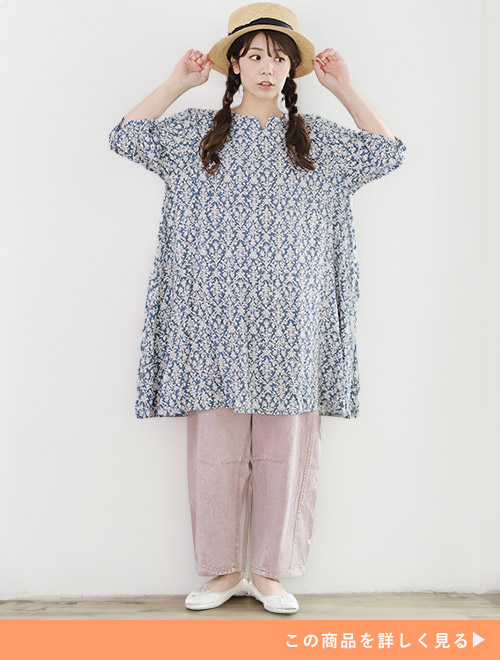 サックスの花柄チュニックにピンクベージュのパンツを合わせる女性