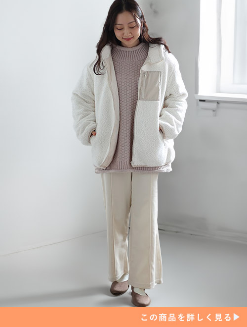 ホワイトパンツとグレーニットのコーデにホワイトのボアフードブルゾンを羽織る女性