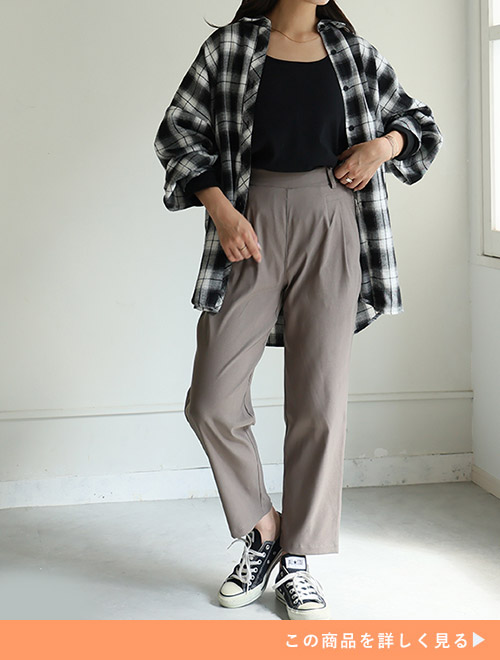 モカのテーパードパンツとブラックトップスのコーデにチェックシャツを羽織る女性