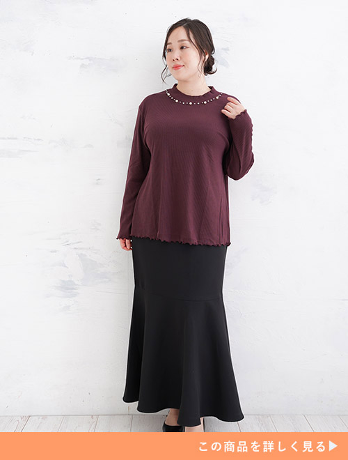 ボルドーのニットを着て、ブラックのマーメイドスカートを履く女性