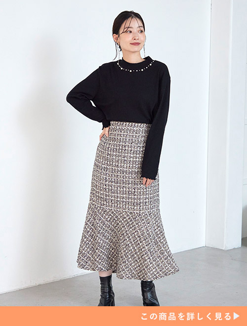 ビジューが付いたトップスを着て、ツイードのマーメイドスカートを履く女性