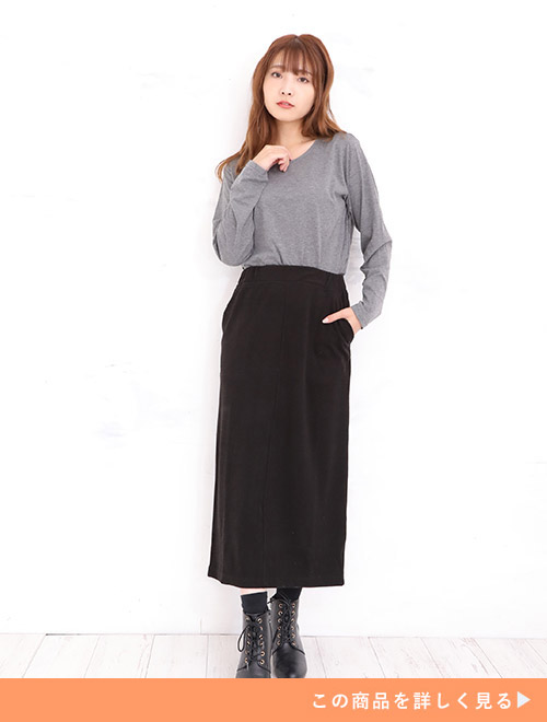 グレーのカットソーを着て、黒のロングスカートを履く女性