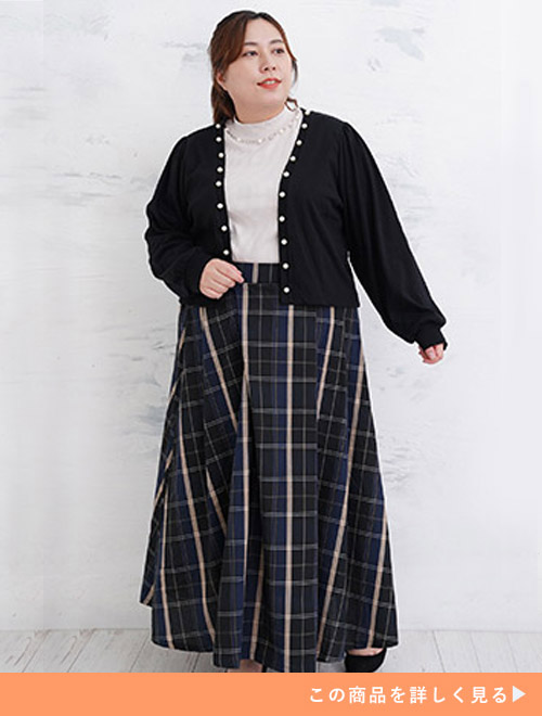 白のトップスに黒のカーデを羽織、チェックのフレアースカートを履く女性