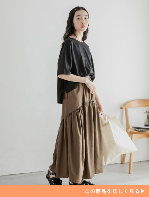 黒のカットソーにブラウンのギャザースカートを履く女性