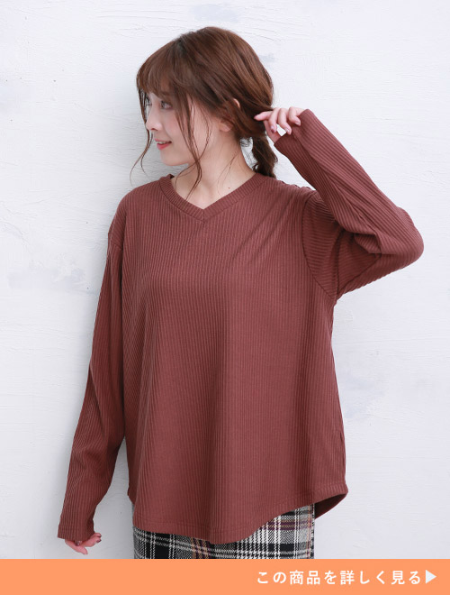 ブラウンのVネックニットを着て、白黒のグレンチェックのボトムを履く女性