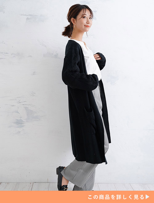 白のトップスにブラックのロングカーディガンを羽織り、ワイドパンツを履く女性