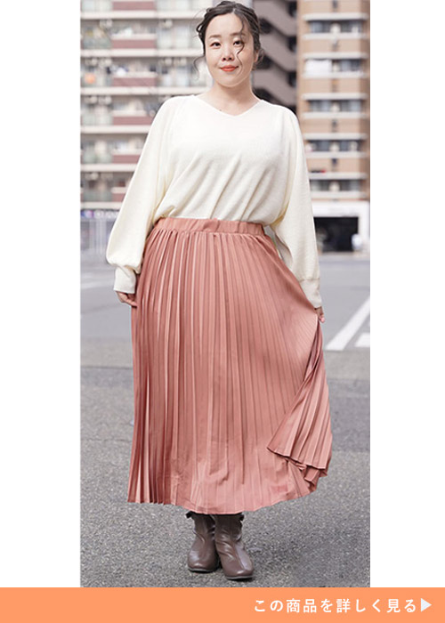 ピンク色のプリーツスカートに、白のトップスをインして着る女性